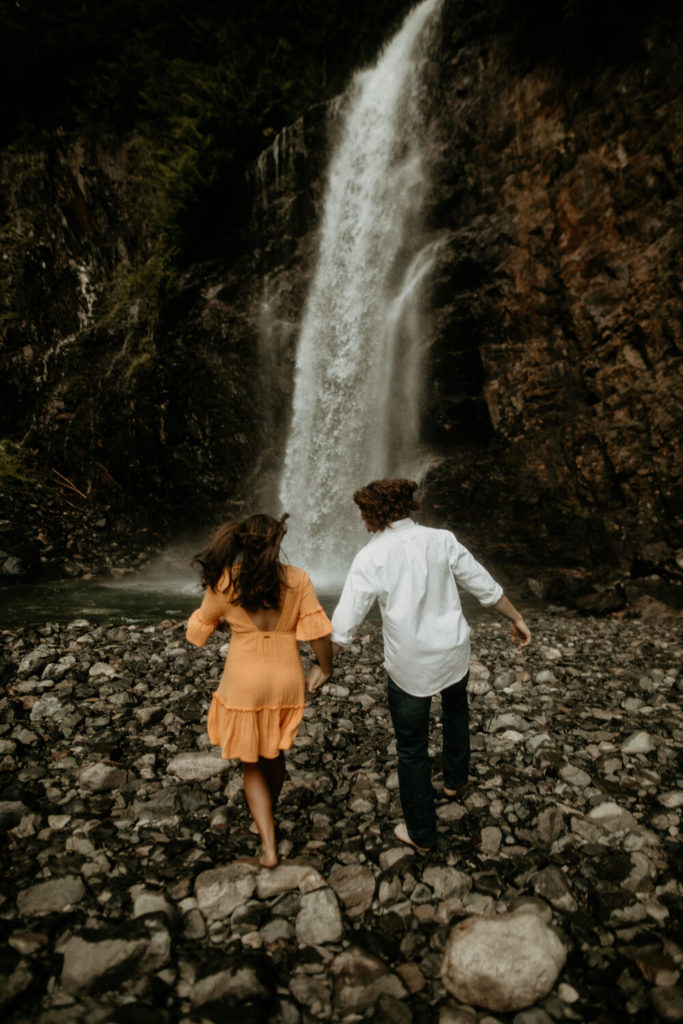 couple walking towards waterfall