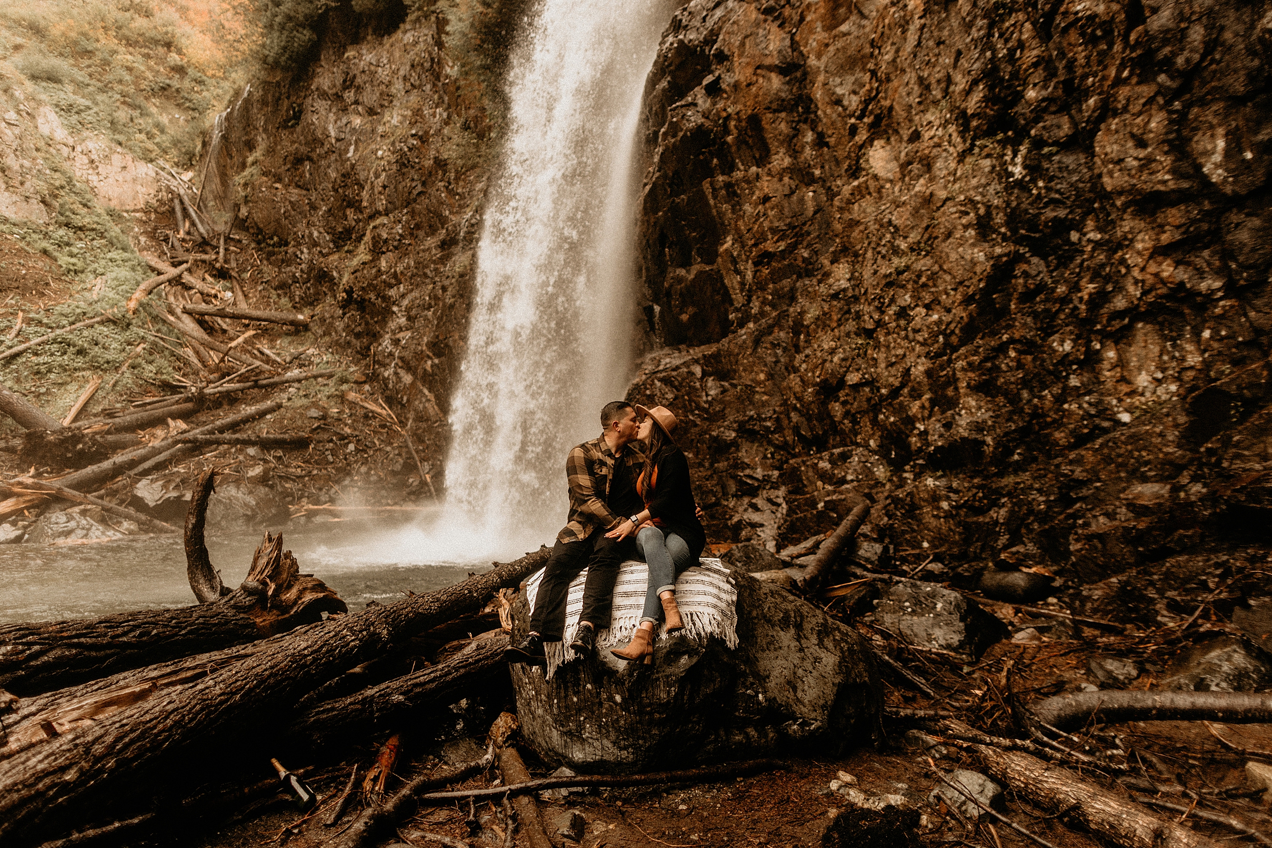 couple sitting and kissing in front of franklin falls