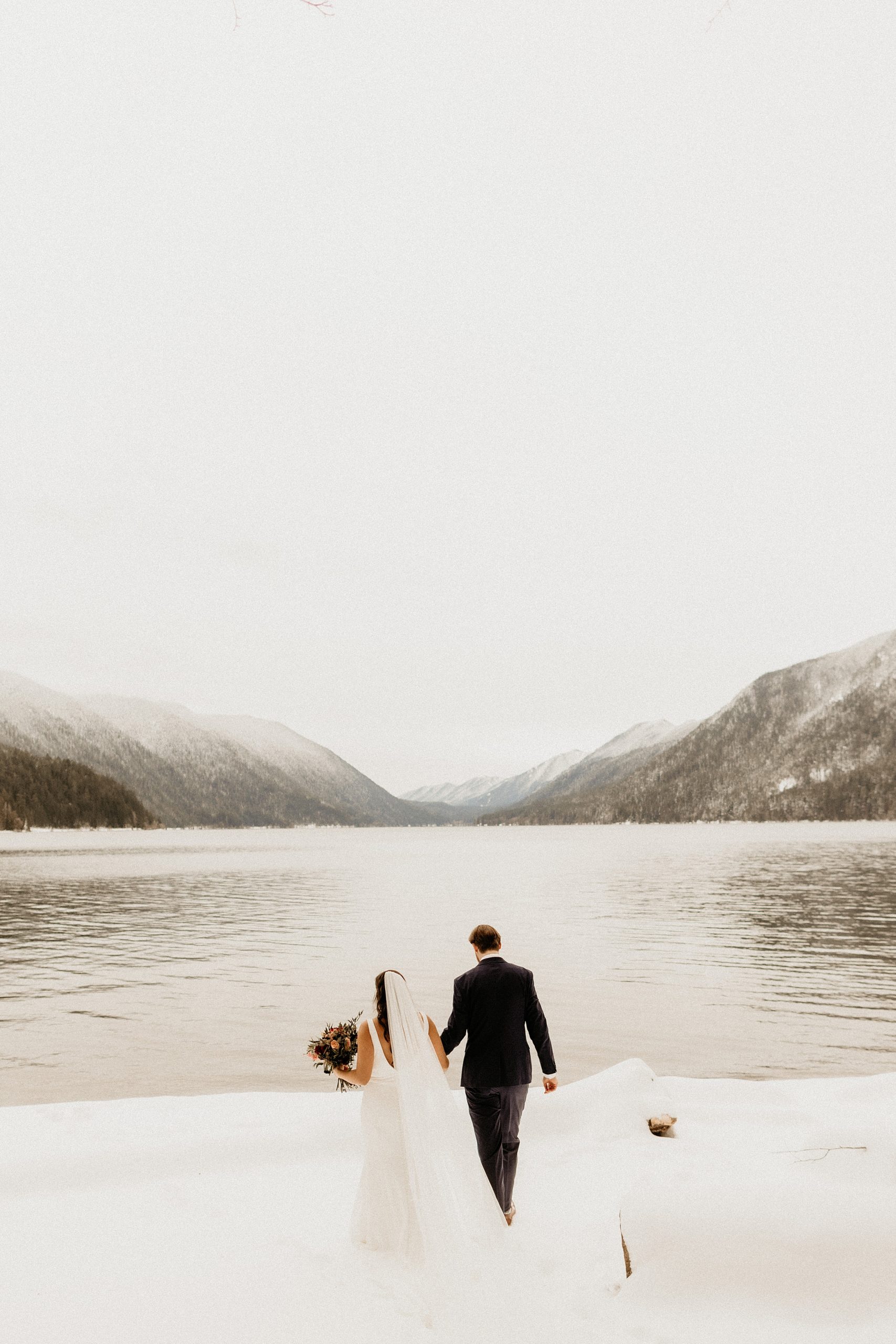 bride and groom standing together lake crescent snow landscape 

