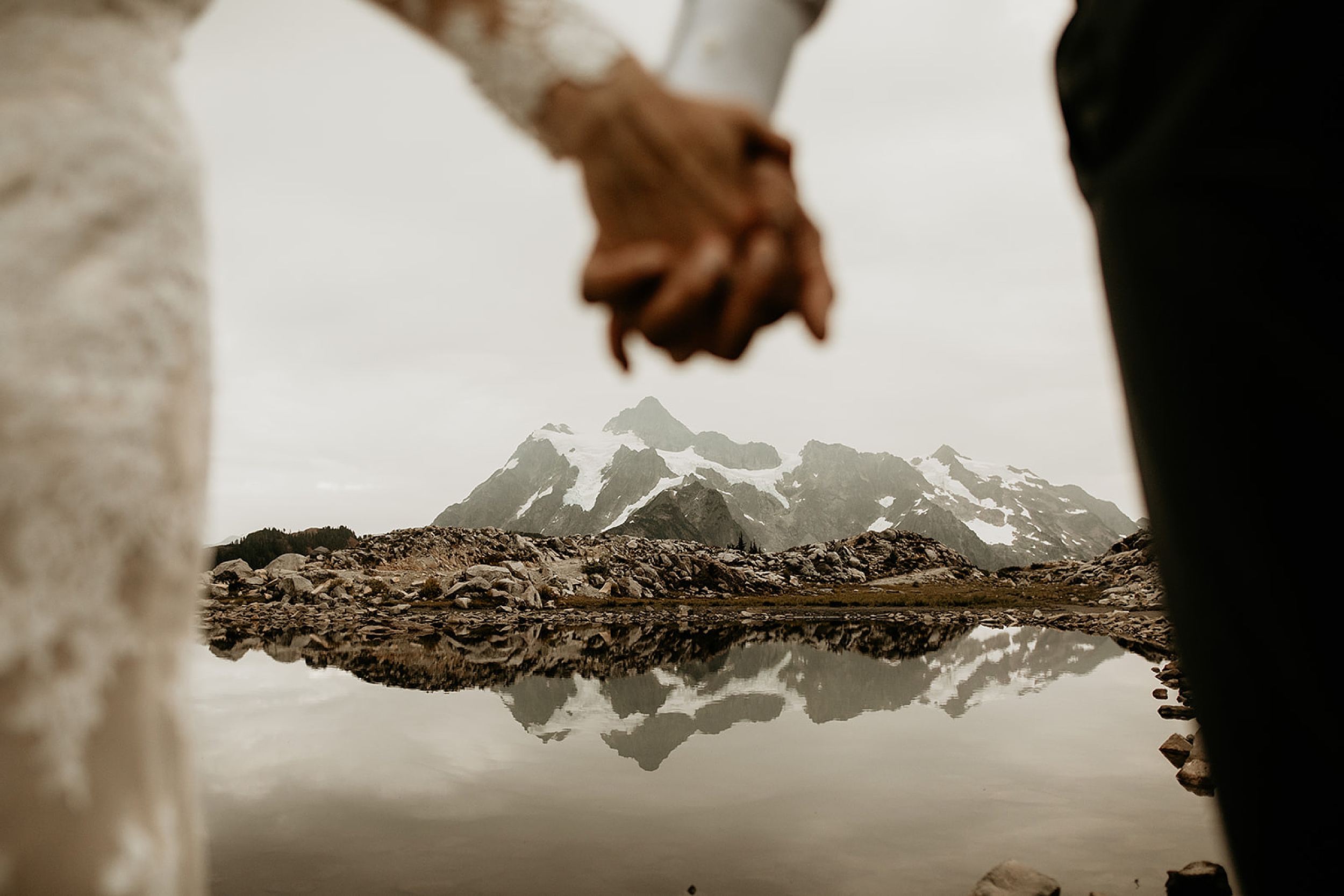 bride and groom holding hands  mountain lake landscape