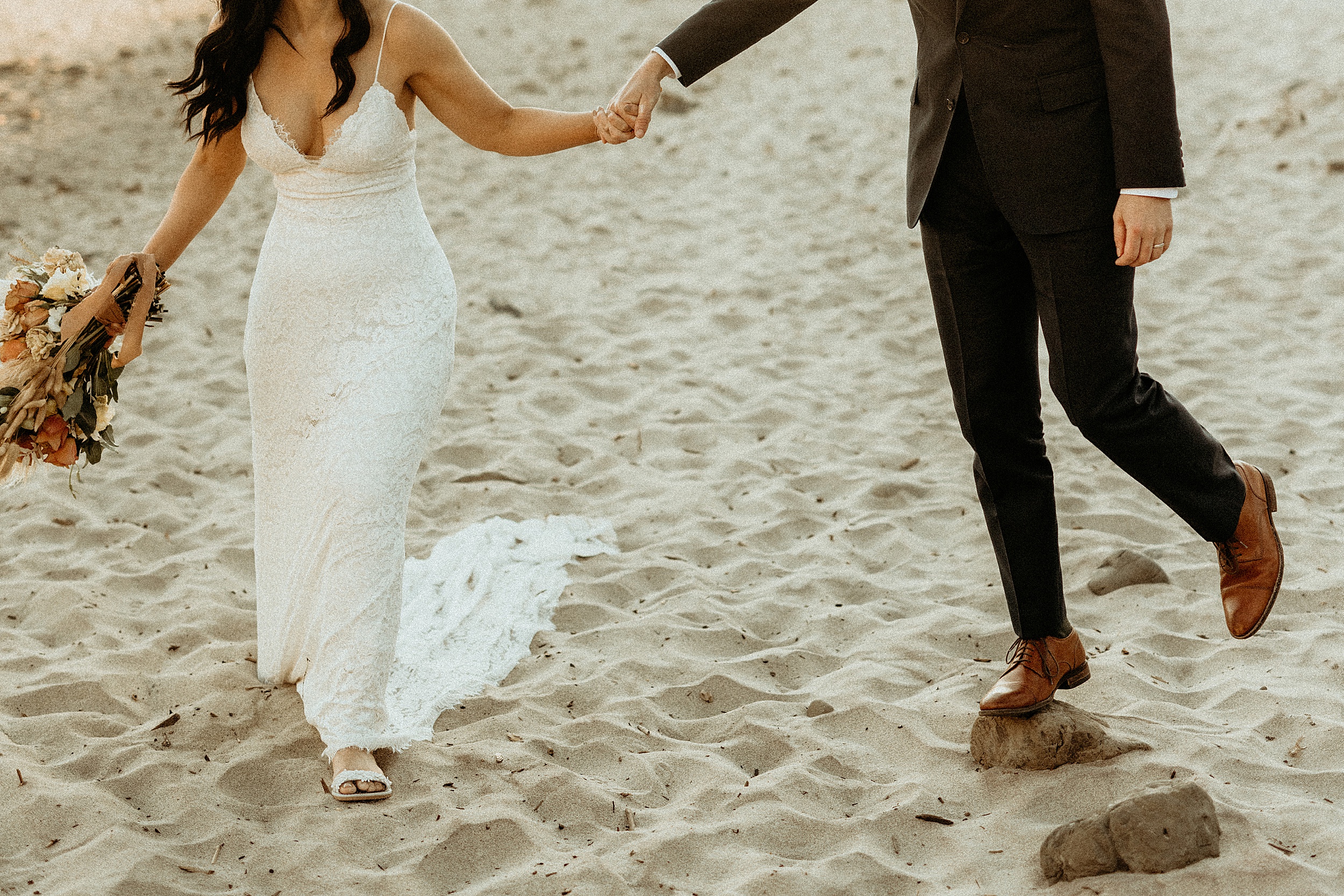 bride and groom walking together keyhole arch at pfeiffer beach landscape 