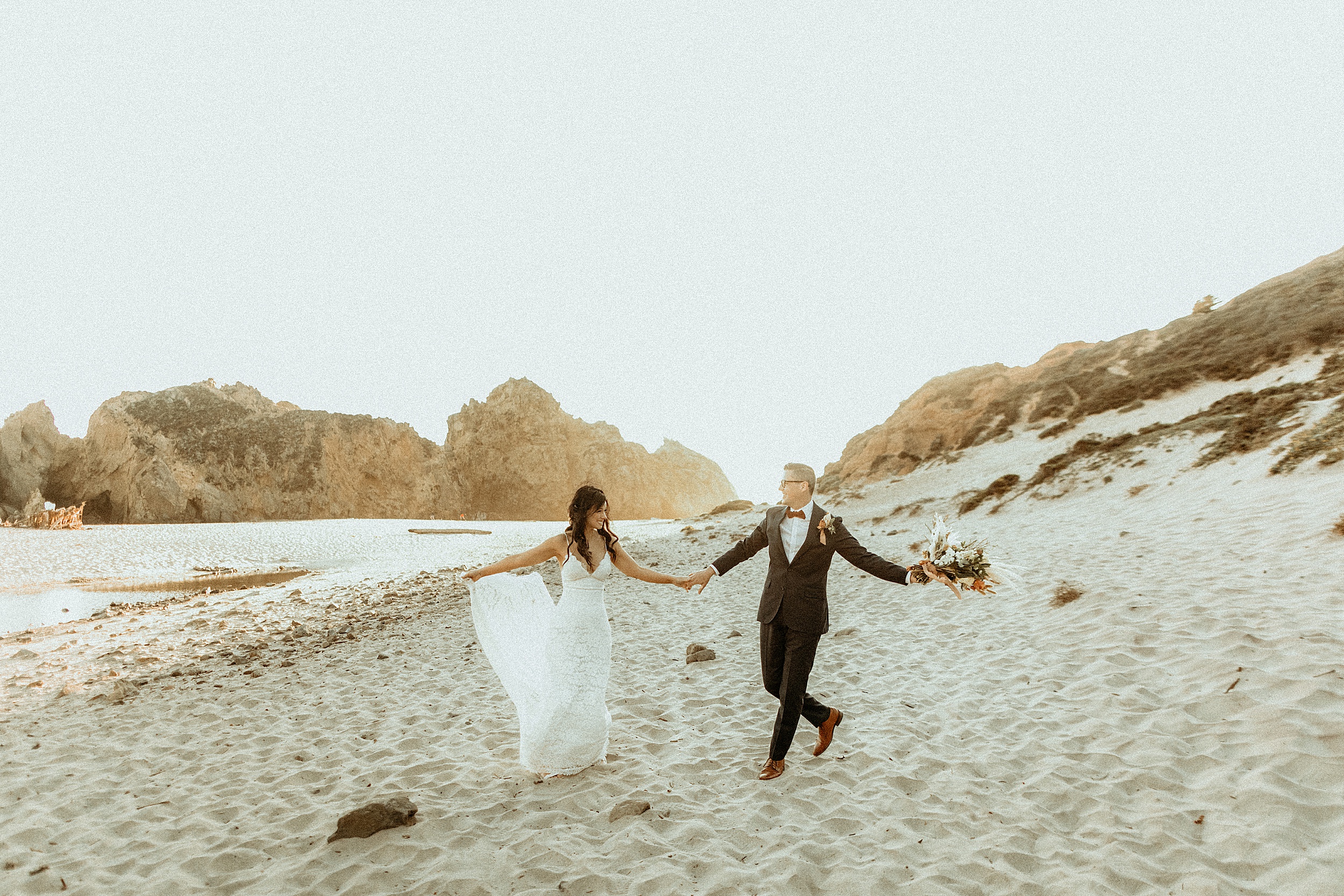 bride and groom walking together keyhole arch at pfeiffer beach landscape 