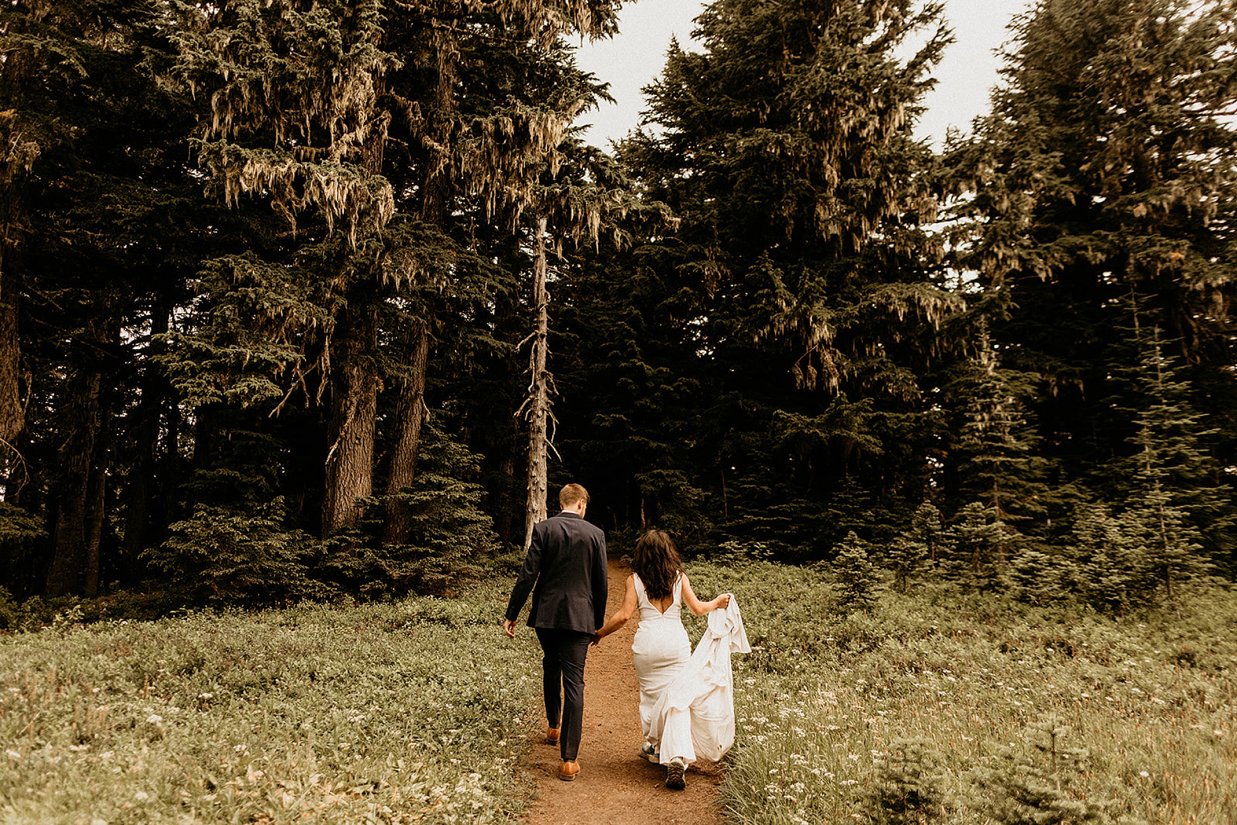 bride and groom walking on trail 