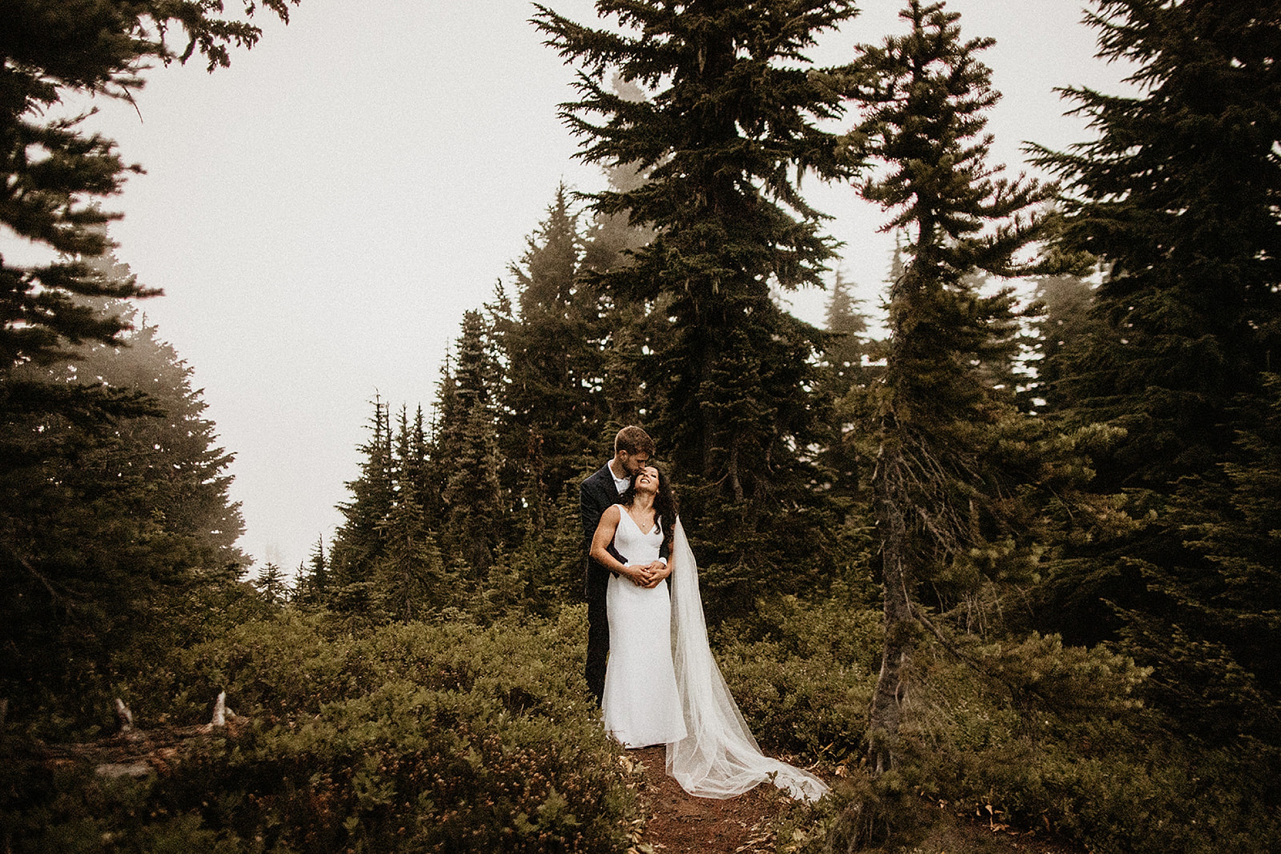 bride and groom holding each other forest landscape 