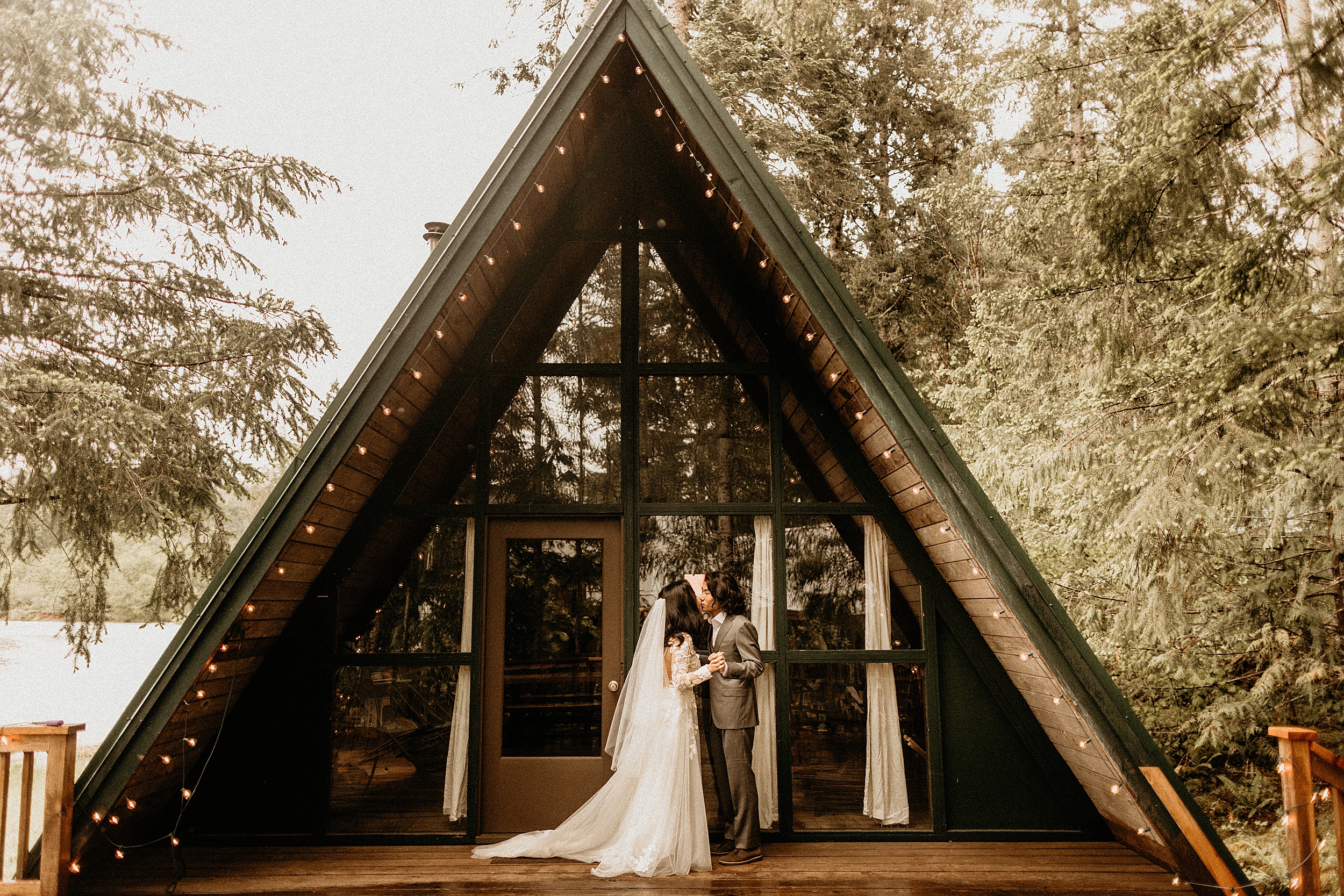 bride and groom standing together a-frame cabin washington landscape
